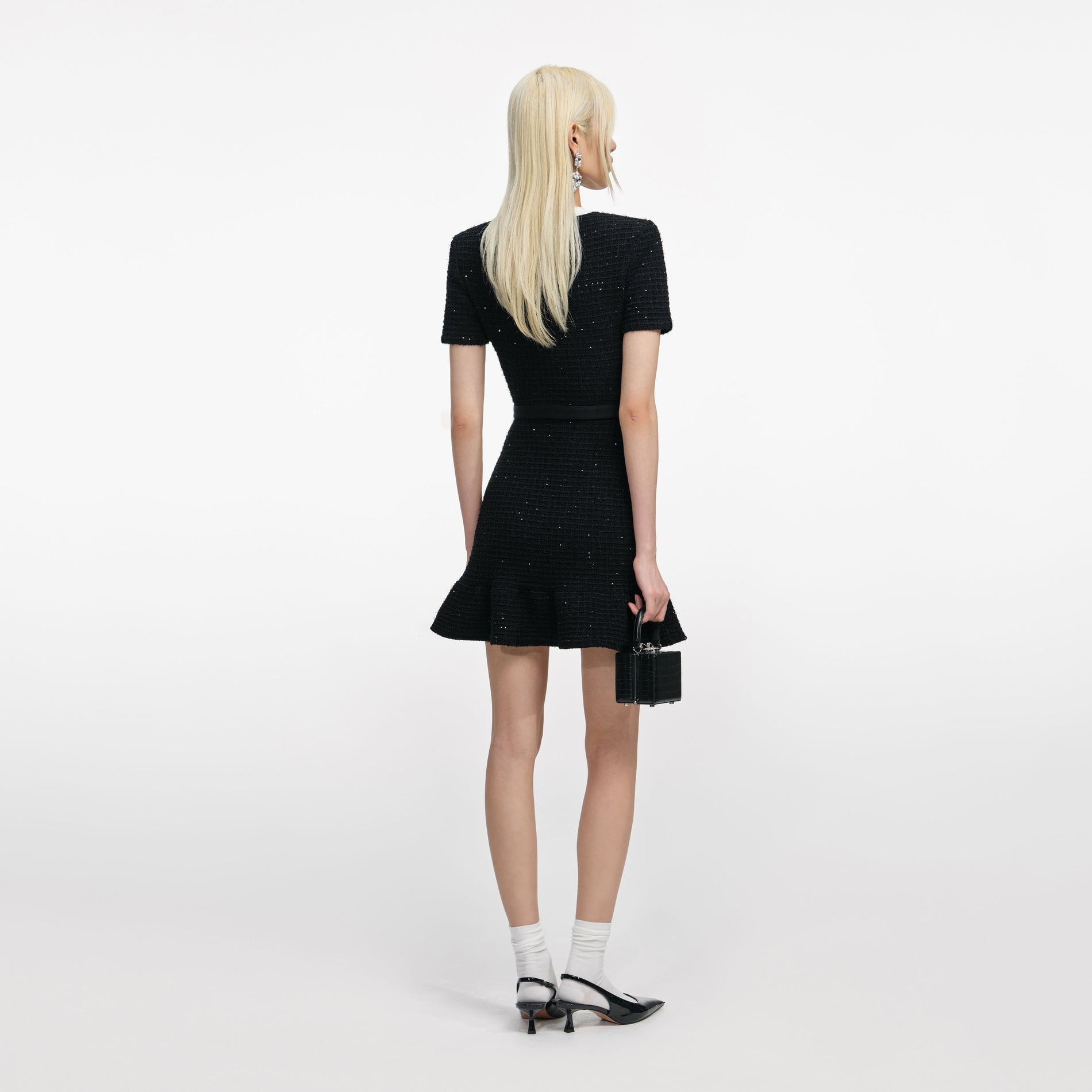 Back view of a woman wearing the Black Floral Textured Knit Mini Dress