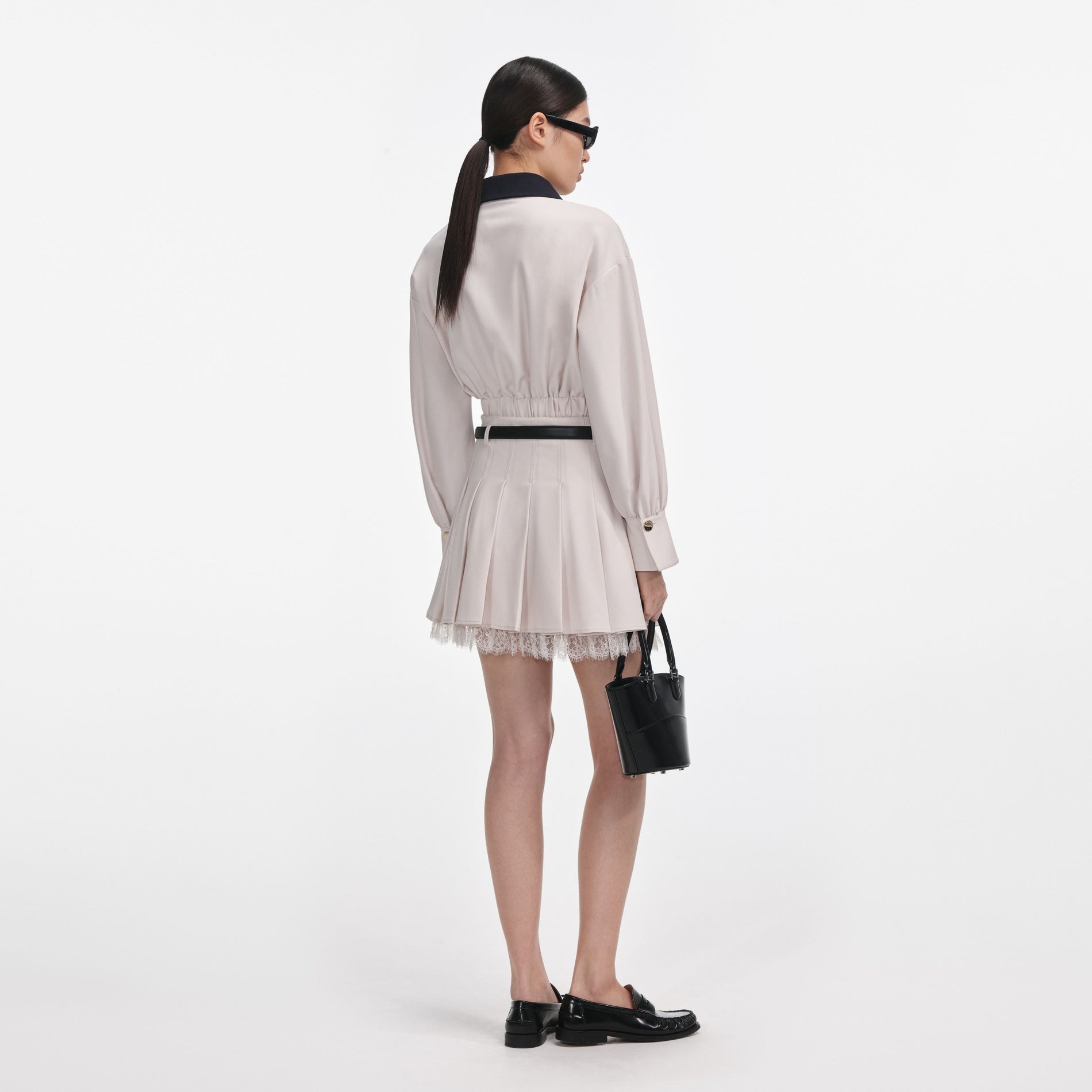 Back view of a woman wearing the Cream Twill Pleated Mini Skirt