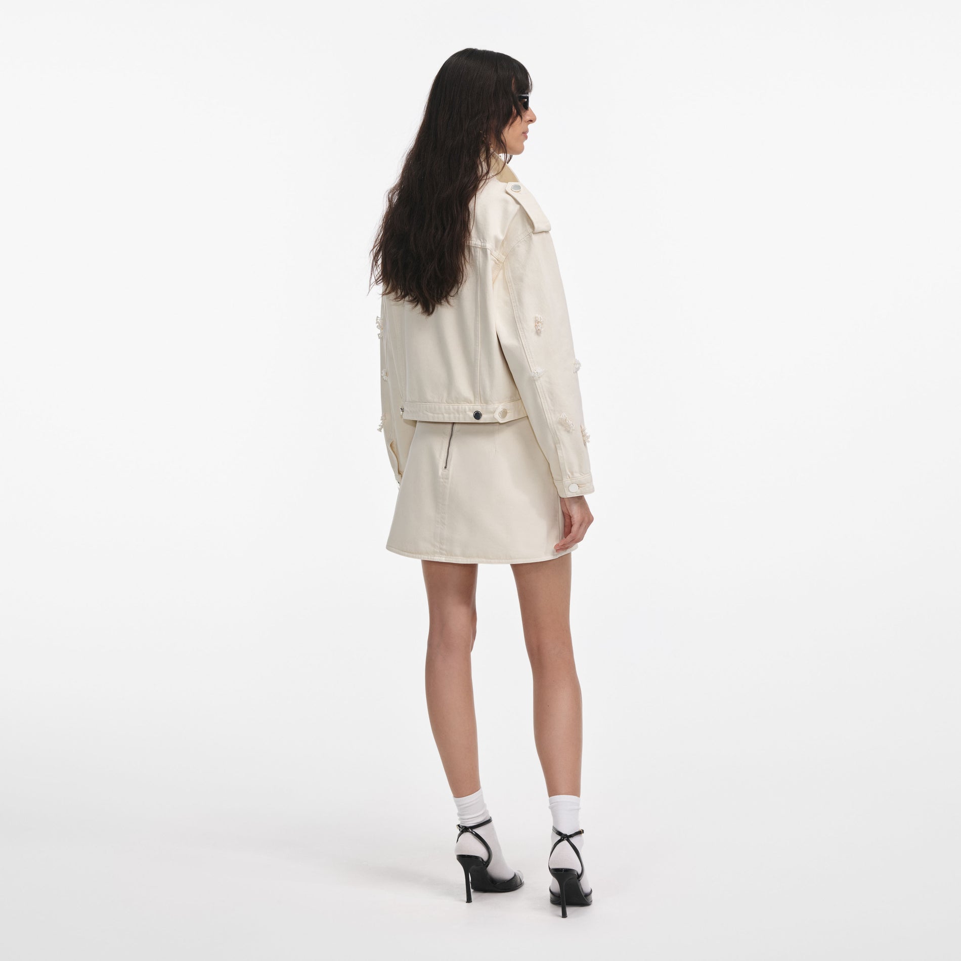 Back view of a woman wearing the Cream Denim Beaded Floral Mini Skirt