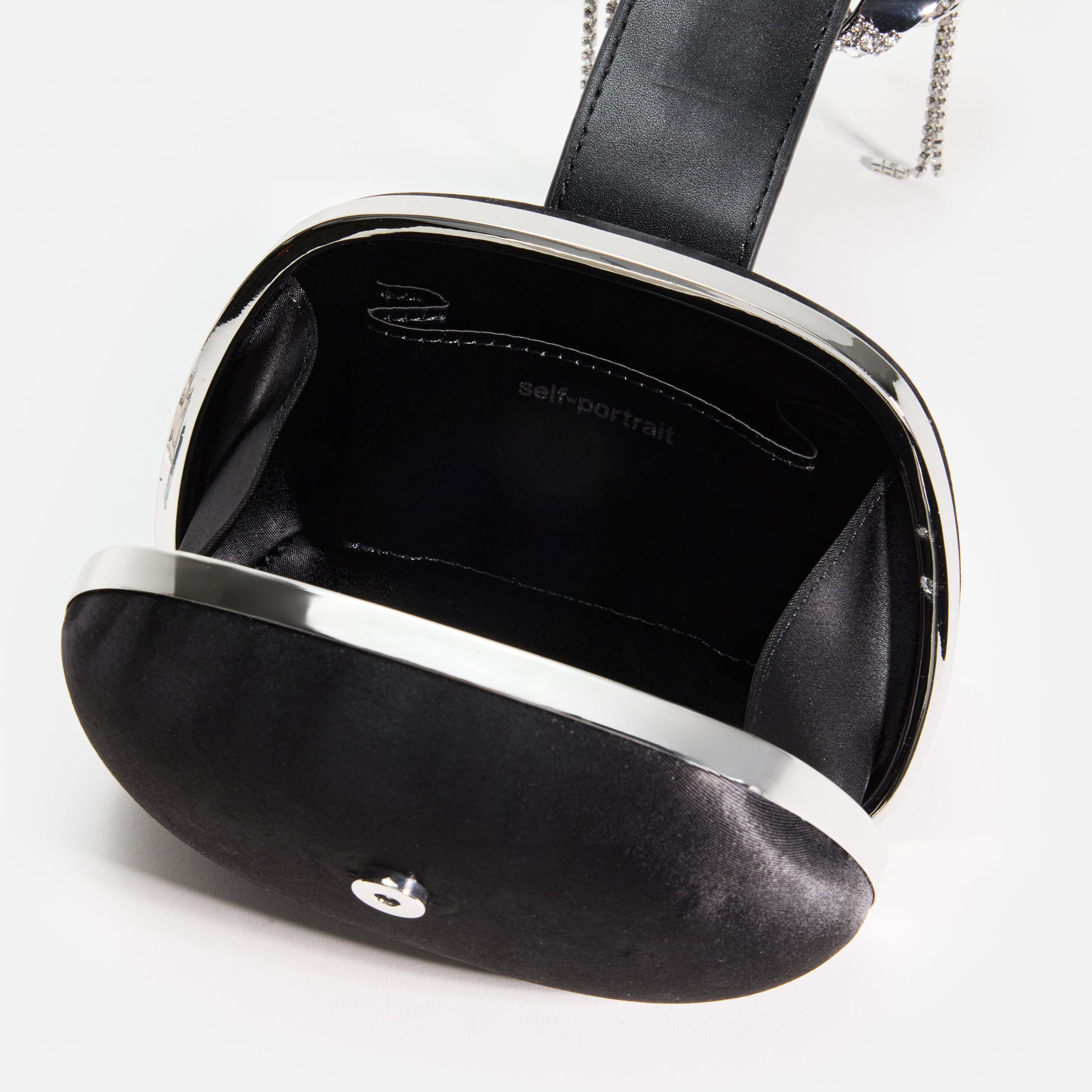 A close up of a woman wearing the Black Satin Top Handle Clutch Bag