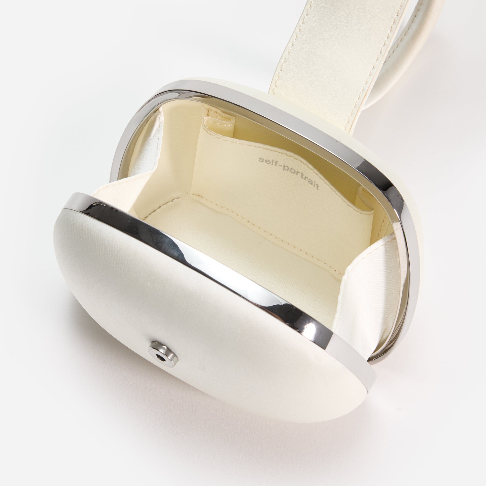 A close up of a woman wearing the Cream Satin Top Handle Clutch Bag