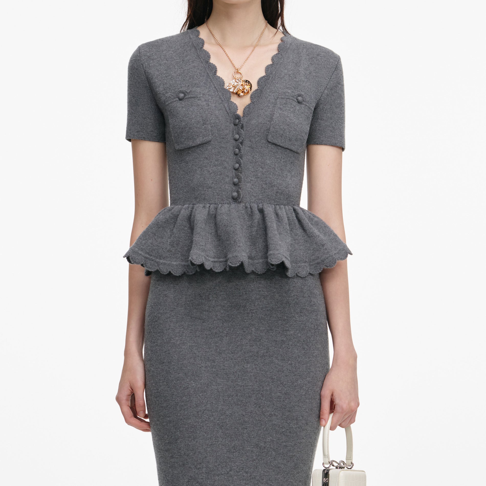 A close up of a woman wearing the Grey Peplum Knit Midi Dress