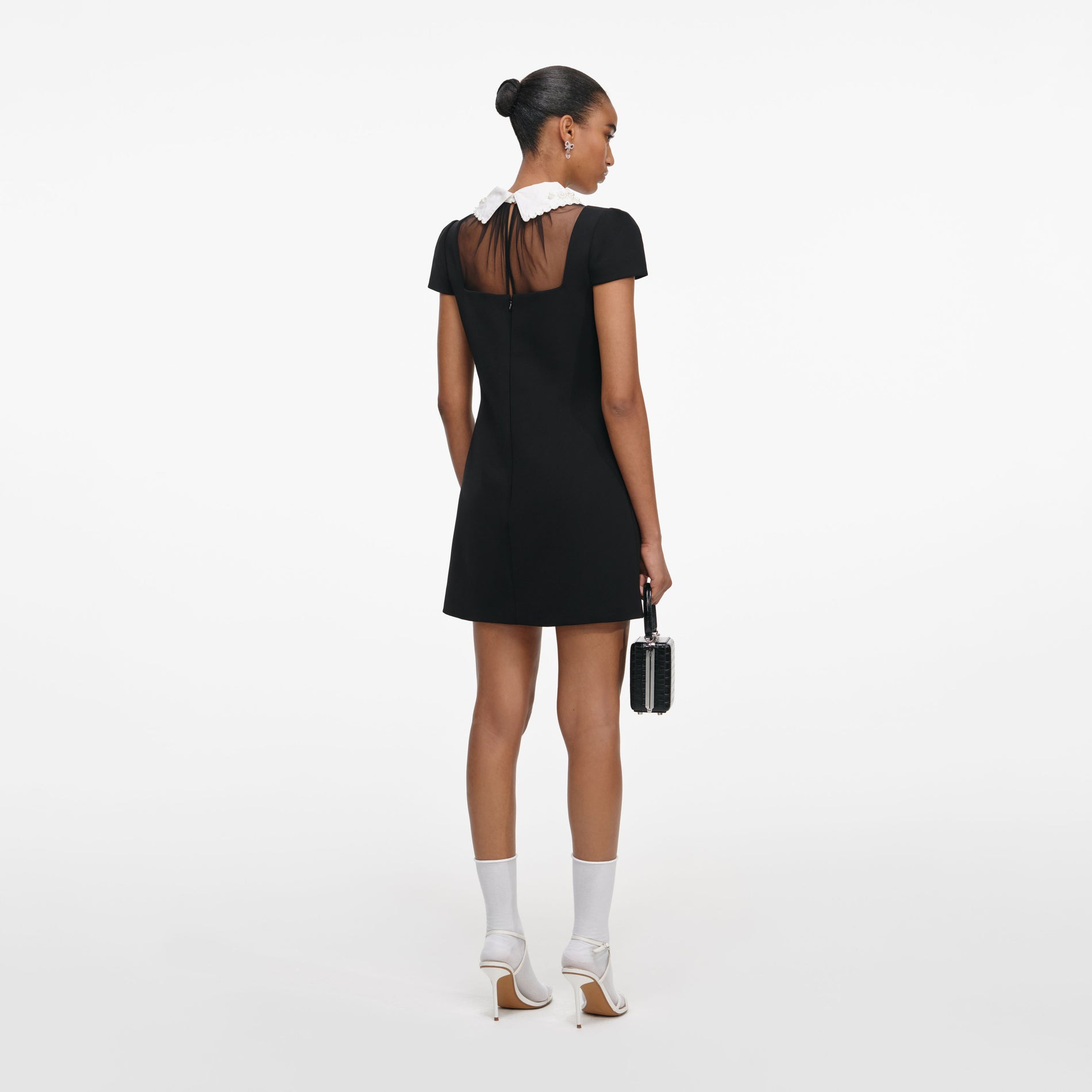 Back view of a woman wearing the Black Crepe Bow Collar Mini Dress