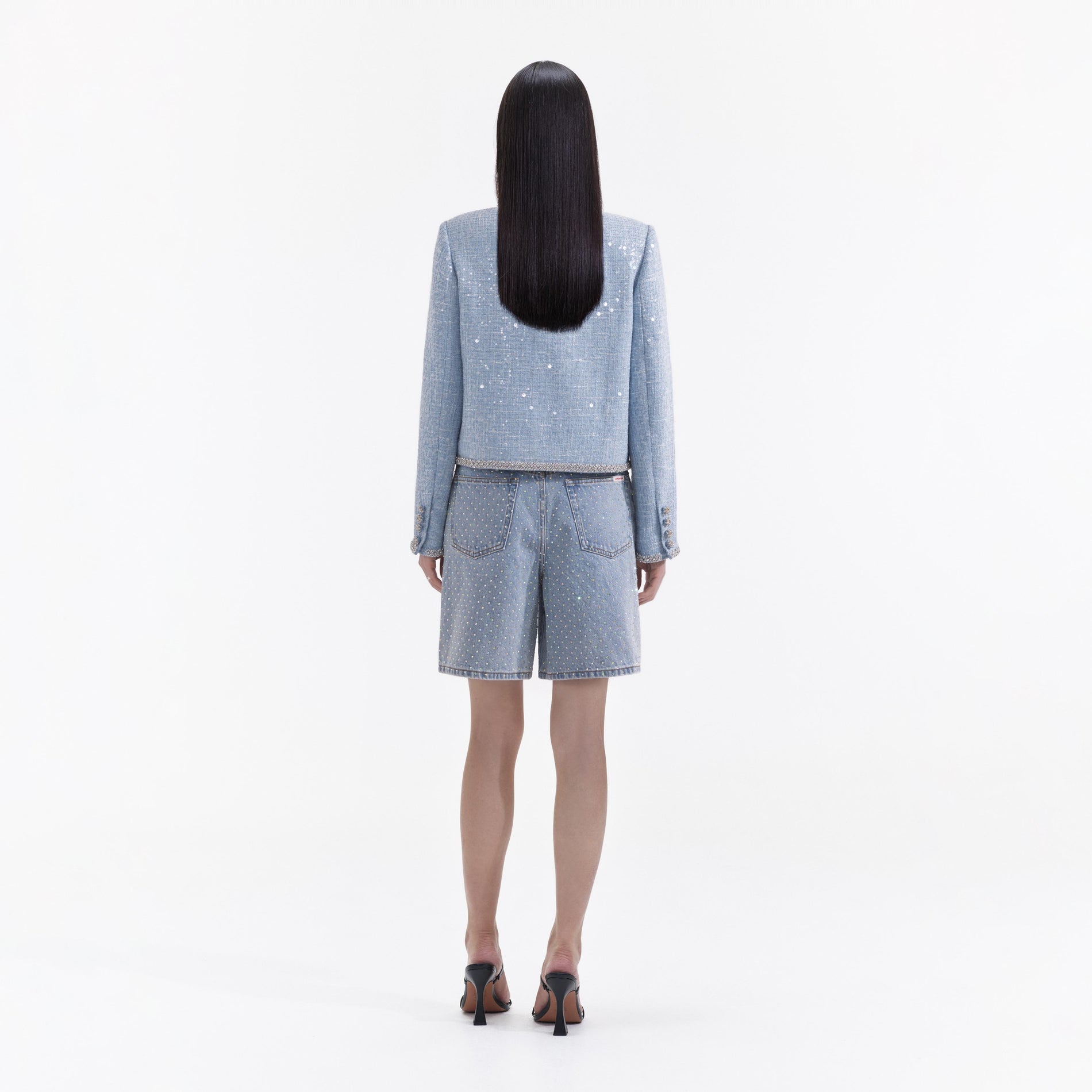 Back view of a woman wearing the Blue Hand Embroidered Chrysanthemum Boucle Jacket