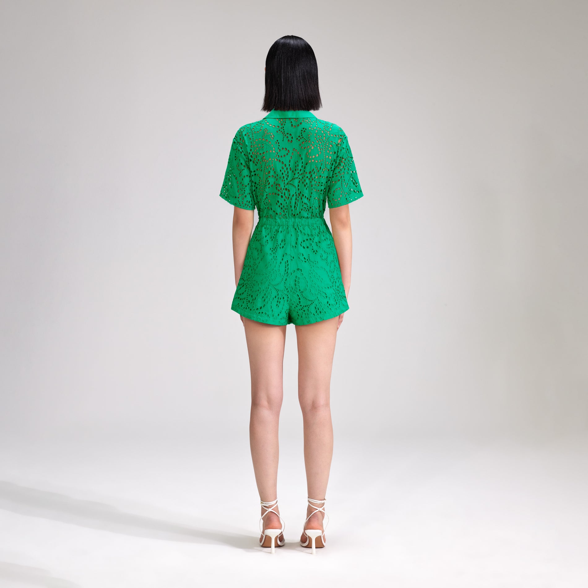 A woman wearing the Green Broderie Playsuit