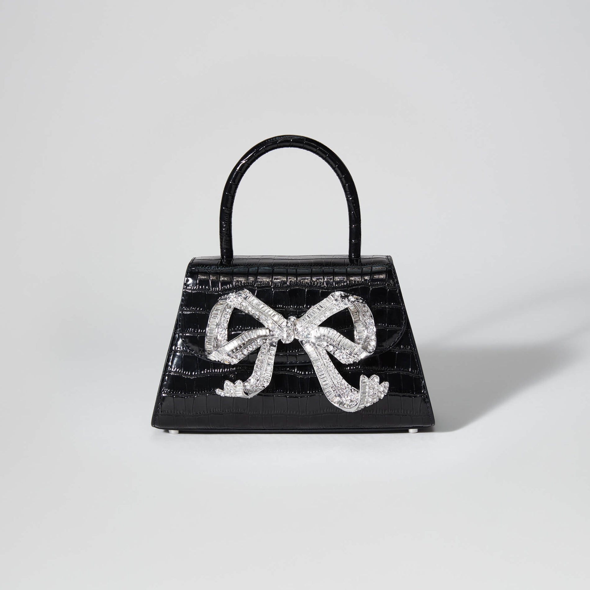 A woman wearing the Black Croc Mini Bow Bag